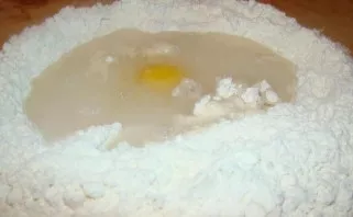 Put flour on the table, make a well and beat the egg. Add salt and half a liter of water.