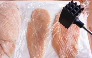 Wash the chicken fillet and cut it lengthwise into 2 parts. Put everything on a cutting board, cover with cling film and lightly line wit...