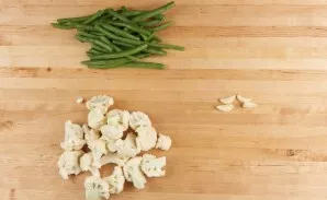 Prepare the ingredients. Divide the cabbage into small inflorescences. Cut the beans in half. Peel the garlic.