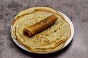 Roll the pancake into a roll. In the same way, prepare all the pancakes.