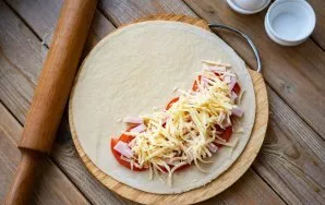 Grate the cheese and spread half on the ham.