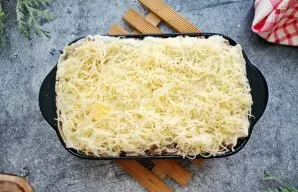 Grease the top sheet of lasagna with the remaining bechamel sauce and sprinkle with grated cheese.