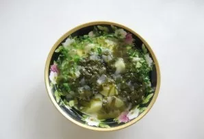 Pour sorrel with potatoes and onions into a plate from a saucepan.