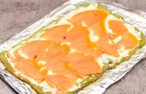 Grease the cake with cream cheese and lay out the fish.