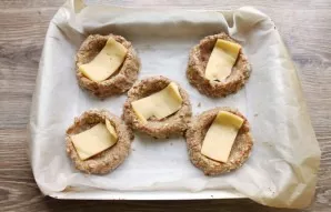 Cut the cheese into slices according to the number of prepared slots. Remove the baking sheet from the oven and add the cheese.