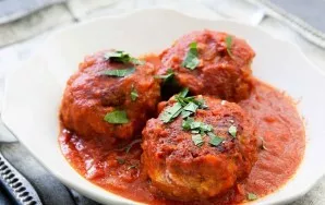 Serve meatballs with sauce, decorated with fresh herbs.