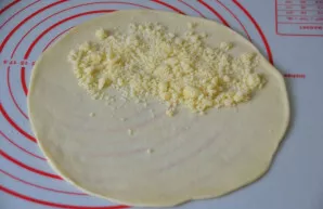 Roll out a thin pancake the size of a baking sheet from the dough and sprinkle with crumbs on one side.
