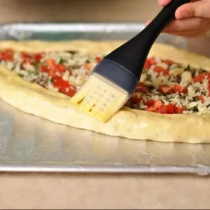 Brush the beaten egg on the sides of the pizza and pour the rest over the filling.
