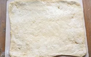 Lightly sprinkle the work surface with flour and roll out the dough with a rolling pin into a rectangular layer about 7 mm thick. Grease ...