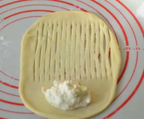 Roll the dough for the second type of buns into an oval. Put the filling on one end, cut lengthwise with a knife or a special roller.