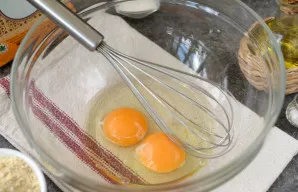 Crack two small eggs into a deep bowl and whisk until frothy.