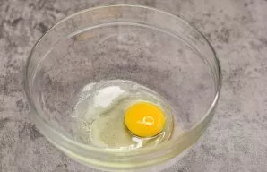 Break an egg into a deep bowl, add salt and sugar.