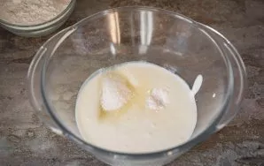 Pour kefir into a spacious bowl, add vegetable oil, salt, sugar, soda. Stir everything with a whisk and wait for the soda to react with k...