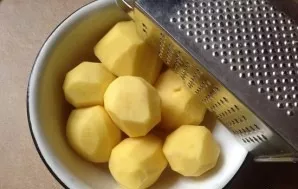 While the cooked potatoes are cooling, we wipe and grate the remaining potatoes with a potato grater.