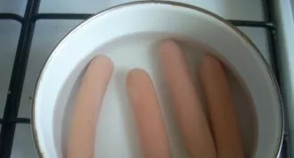 Pour water into another pot and add the sausages. Put on the stove and bring to a boil. Cook the sausages over low heat for about five mi...