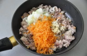 Pour vegetable oil into a preheated pan, add mince, fry for 2-3 minutes, then add finely chopped onion, grated carrots and garlic.