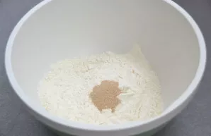Pour sifted flour and dry yeast into the bowl for kneading the dough, mix.