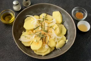 Cut the potatoes into slices 3-4 mm thick, add the onion chopped in half rings and thin slices of garlic and rosemary. Pour a tablespoon ...