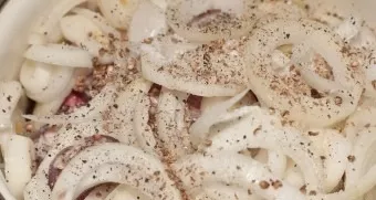 We transfer the pork to a wide saucepan, sprinkle with peeled onion rings, pepper and coriander.