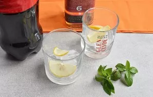 Fill the chilled glasses of ice with a third. Lay out the lemon slices, cut them in half.
