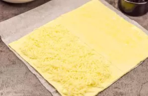 Roll out the puff pastry and cut it in half. Break the egg into a bowl and shake with a fork. Brush the dough with an egg. Put grated che...