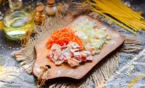 Finely chop the bacon and peel the vegetables. Grate the carrots, cut the onion into small cubes.