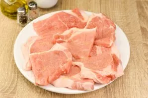 Cut the pork into large pieces, then beat it with a kitchen hammer. Salt and pepper every piece of meat.