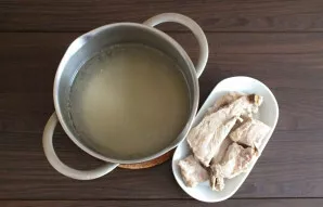 Boil the pork ribs in 2 liters of water. Strain the broth. Cut off the ribs. Cut into pieces and set aside.