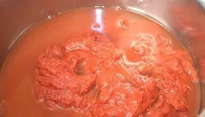 Pour water into a pan with tomato paste and stir. Place the pan on the fire.