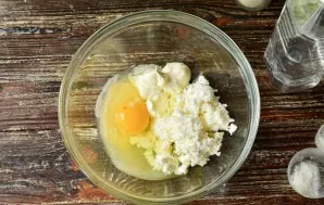 Break an egg into a bowl, add cottage cheese and sour cream.