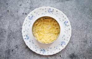 Place the baking ring on a serving dish. Peel the potatoes and grate them on a coarse grater. Place the potatoes in a ring and press down.