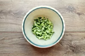 Cut the cucumbers into strips and put them in a salad bowl.