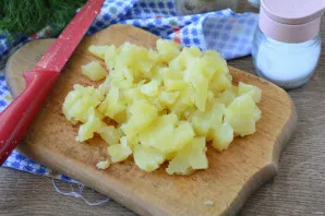 Boil the potatoes, cool, peel and cut into cubes.