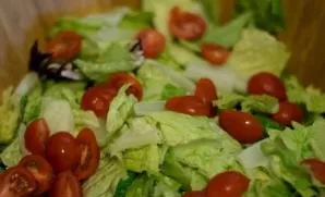 Wash the cherry tomatoes and cut them in half. Add to the salad bowl.