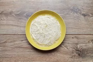 Grate the potatoes coarsely and lay out in an even layer in a serving container or salad bowl. Apply a layer of mayonnaise to the top.