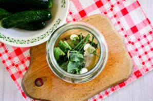 Add spices  garlic cloves, peppercorns, bay leaf and herbs  to the bottom of sterilized jars. Lay out a few dried dill sprigs and a crush...