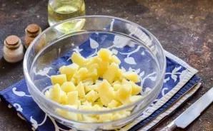 Cut the potatoes into small cubes and immediately transfer to a salad bowl or to a deep container.