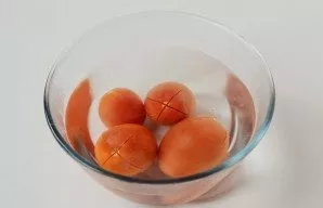 On top of the tomatoes make a cross-shaped incision, pour boiling water for 10 minutes. Then remove the skin and chop finely.