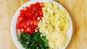 During this time, wash, dry and chop tomatoes, artichokes, garlic and herbs. Grate hard cheese.