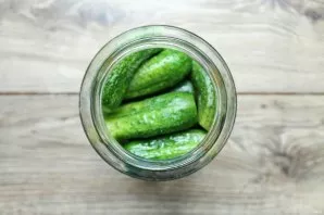 Wash the cucumbers thoroughly, cut off the tips and put them tightly in prepared jars. Put the leaves on top.