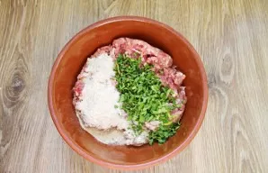 Finely chop parsley and basil and add to a bowl with minced meat, bread crumbs and egg.
