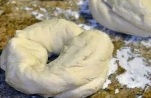Divide the risen dough into small pieces, form rings from them, strongly pinching the edges.