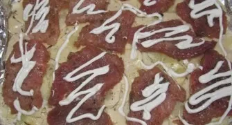 Cut the pork into portions, lightly knock out and put on top of the potatoes. Sprinkle with salt and pepper, coat with mayonnaise.