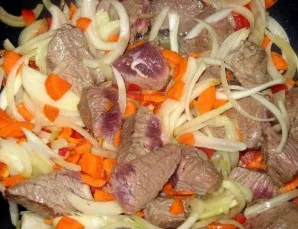 We send finely chopped onions and carrots to the meat. Mix everything thoroughly and cover with a lid, slightly reducing the heat.