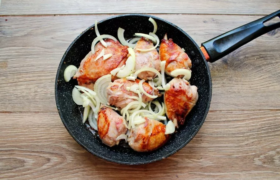 Peel the onion and cut it into half rings, put it in the pan with the chicken. Stir everything and fry on medium heat for 7 minutes.