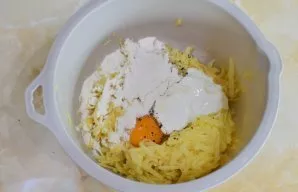 To make the dough, grate the potatoes on a coarse grater. Drain the liquid. Break an egg into the potatoes, add sour cream and flour. Spr...
