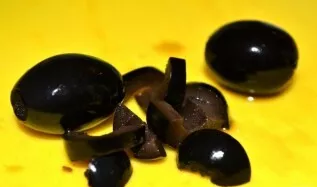 I take the olives out of the jar, cut each into 2 parts, then chop them.