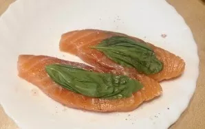 The fish should marinate for 10 minutes. Then we cover the fish slices on both sides with basil leaves.