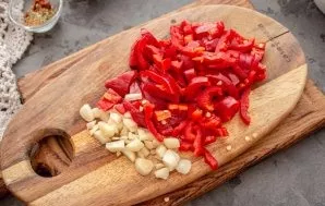 Remove the seeds of peppers, cut the pulp into thin short strips. Cut the garlic into small pieces. Put them in a pan and fry for a coupl...
