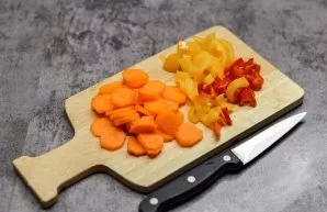 Peel carrots and bell peppers, wash and dry the vegetables. Cut the carrots into slices, cut the peppers into small strips.